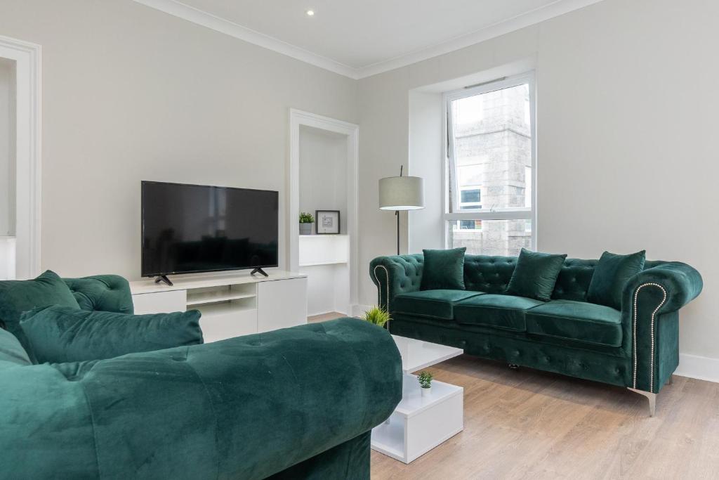 sala de estar con 2 sofás verdes y TV de pantalla plana en Luxury 3 Bed Apartment in Aberdeen City Centre. en Aberdeen