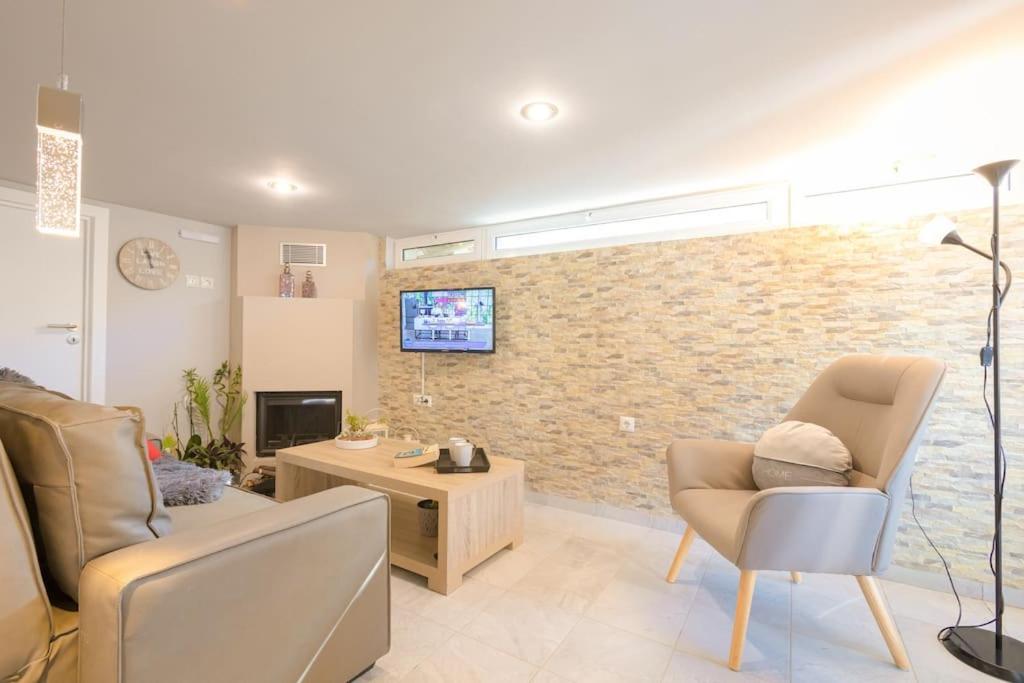 ein Wohnzimmer mit 2 Stühlen und einem TV an einer Backsteinwand in der Unterkunft Santa Barbara lux studio in Marathonas in Lófos