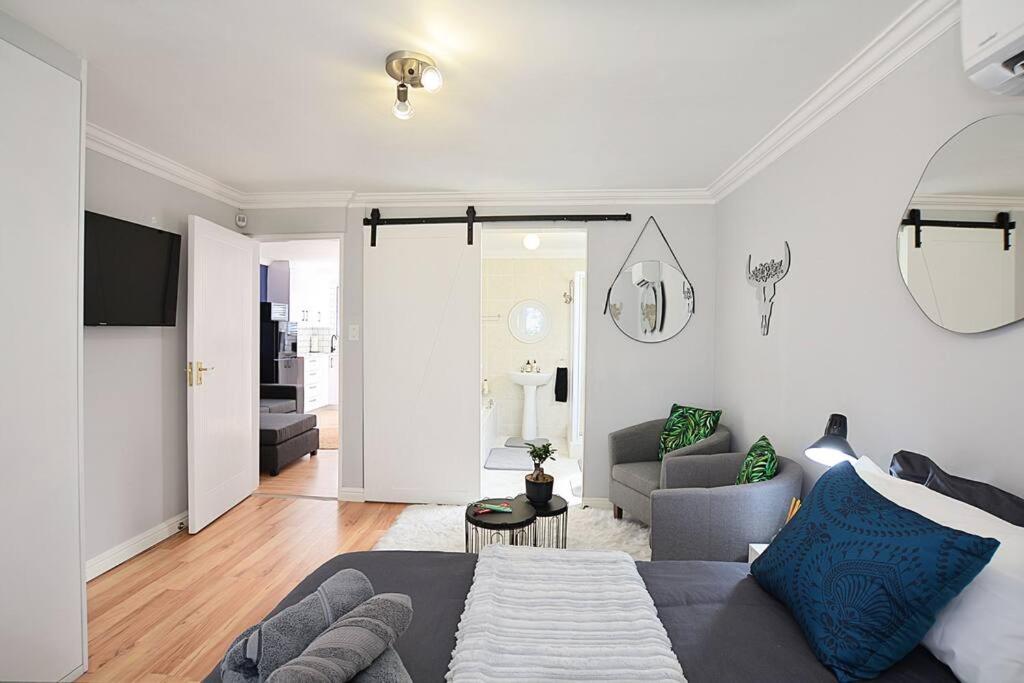 a bedroom with a bed and a living room at Flatlet 2.1km from Iconic Blaauwberg Beach in Cape Town