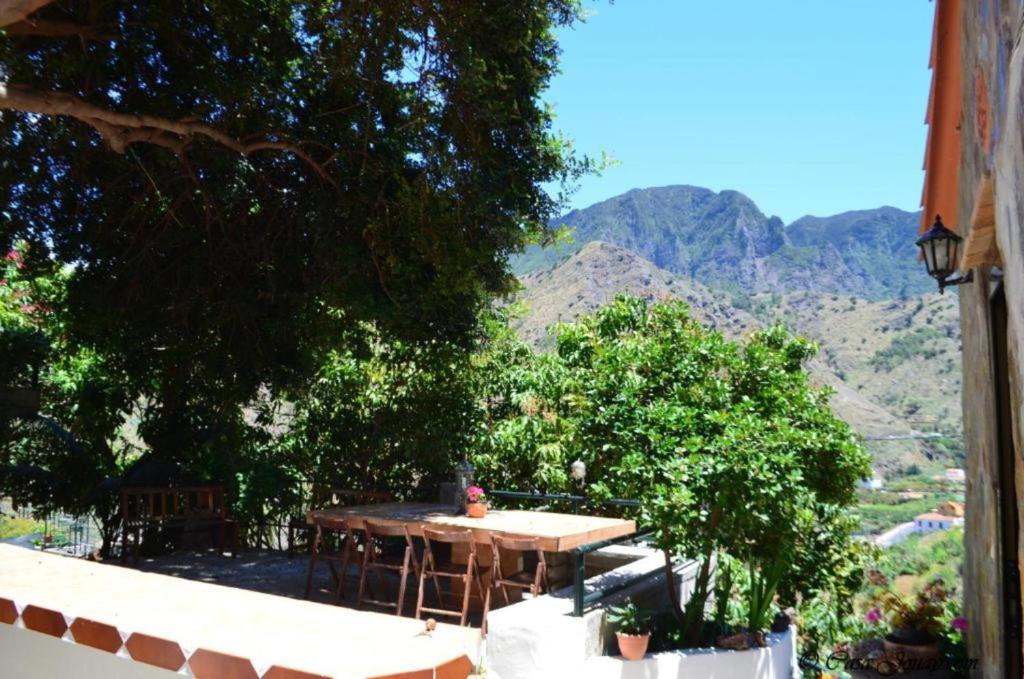 a table on a balcony with mountains in the background at Casa rural con Wifi y estupenda vista a la montaña en Hermigua in Hermigua