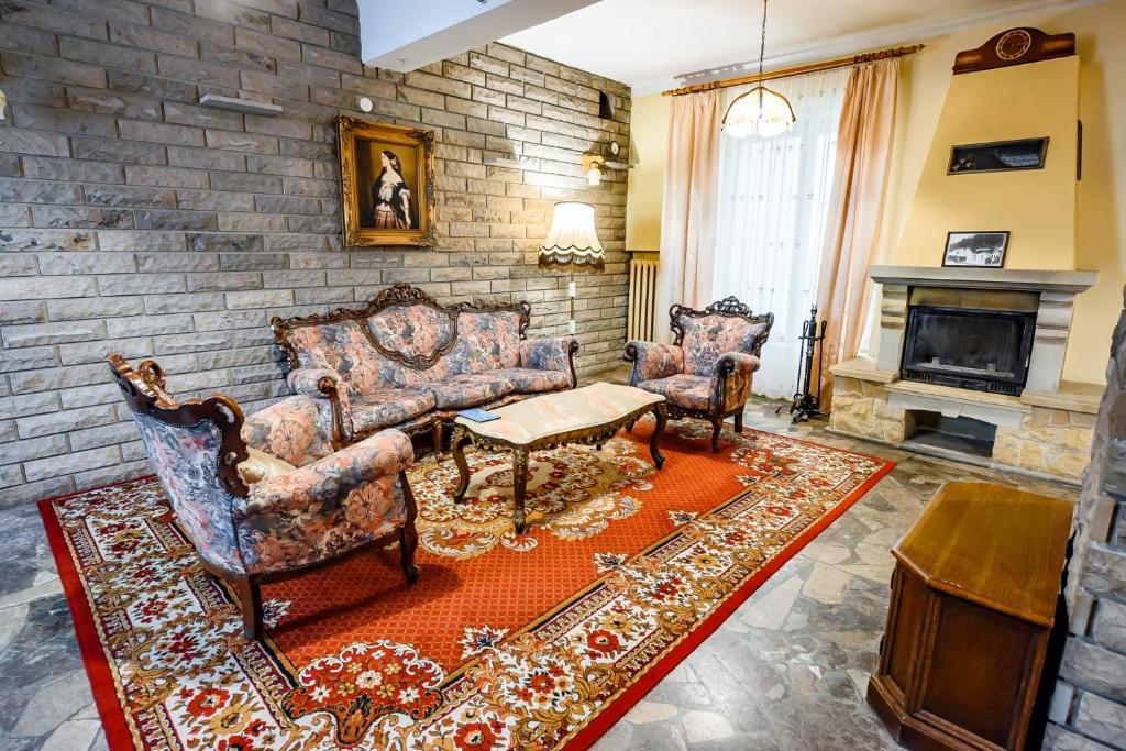 a living room with two chairs and a fireplace at Willa Flora in Krynica Zdrój