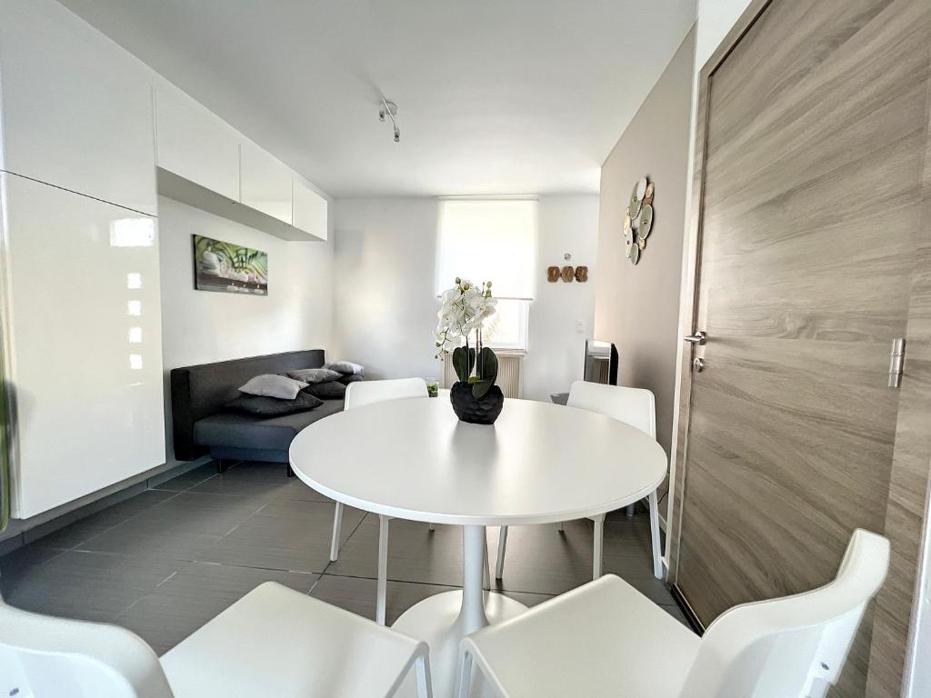 uma sala de jantar branca com uma mesa branca e cadeiras brancas em Robert 20 Brussels-charleroi-airport em Charleroi
