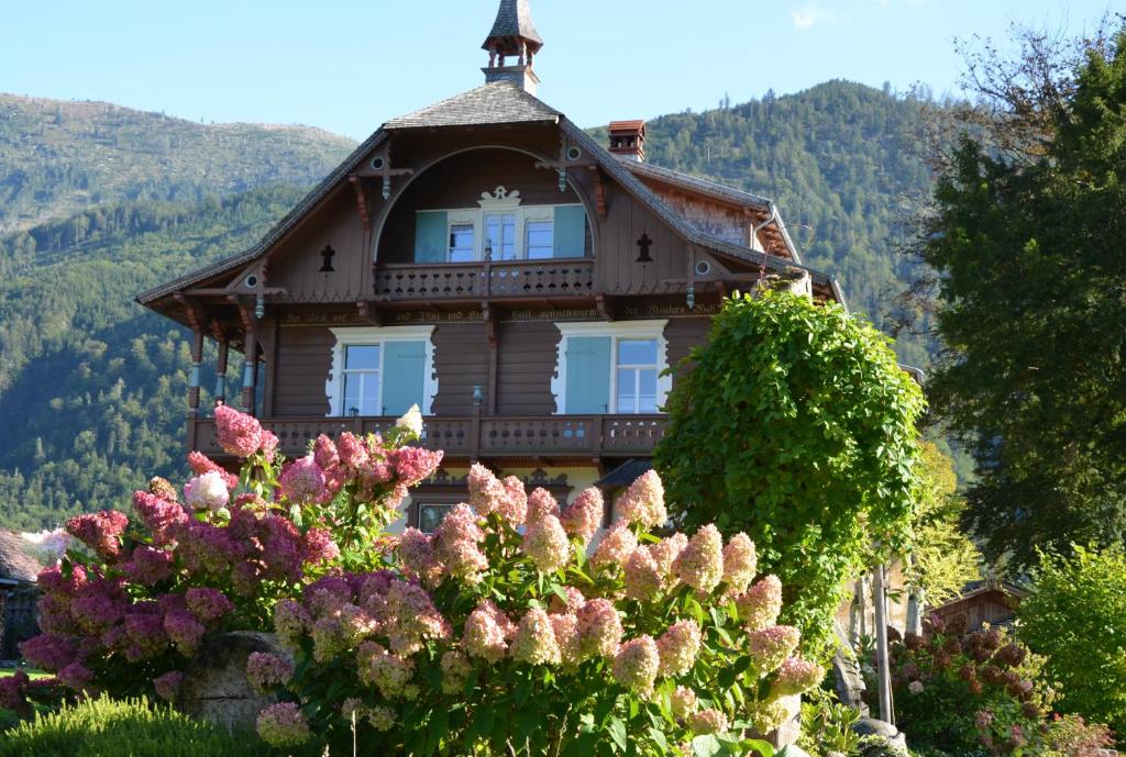 ein Haus mit einem Kreuz auf einem Hügel mit Blumen in der Unterkunft Wohnen am See Villa Schrötter direkt am Traunsee in Rindbach