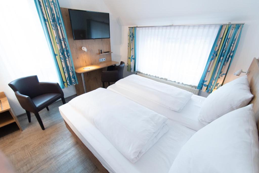 a bedroom with a white bed with a window and a chair at Taste Smart Hotel Backnang in Backnang