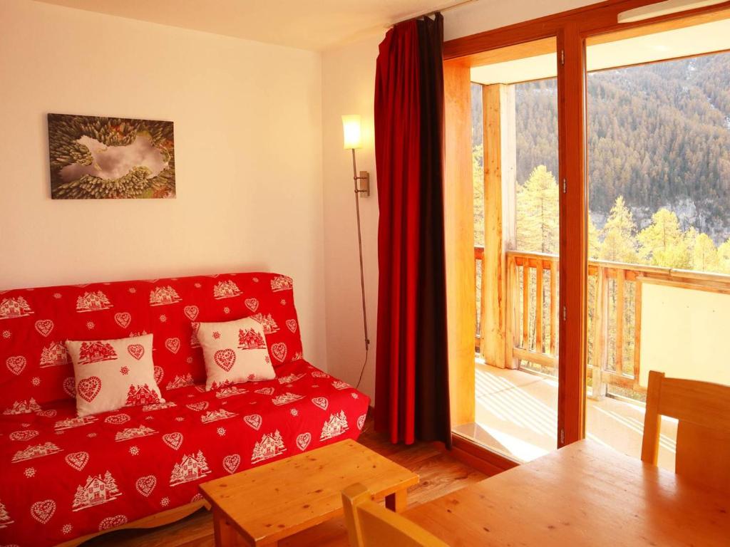 - un salon avec un canapé rouge et une grande fenêtre dans l'établissement Appartement 4 pers, piscine, jacuzzi & skis aux pieds - Les Orres - FR-1-322-425, aux Orres