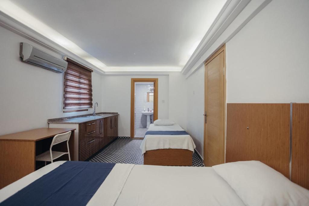 a room with two beds and a desk and a sink at Deniz Pansiyon in İzmir