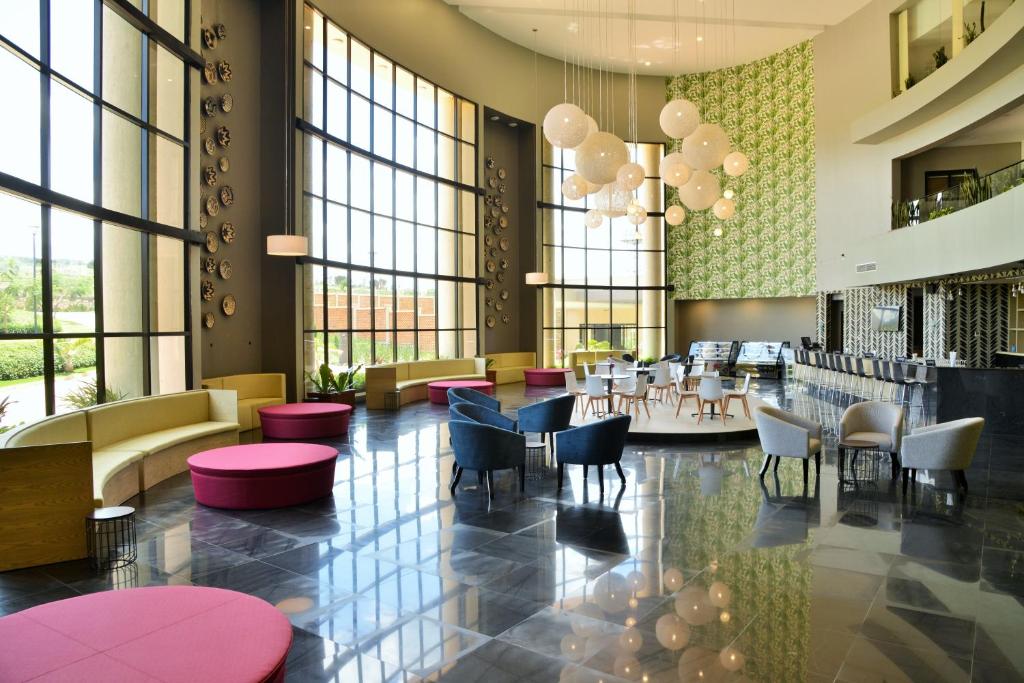 a restaurant with tables and chairs and large windows at EPIC Hotel & Suites in Nyagatare