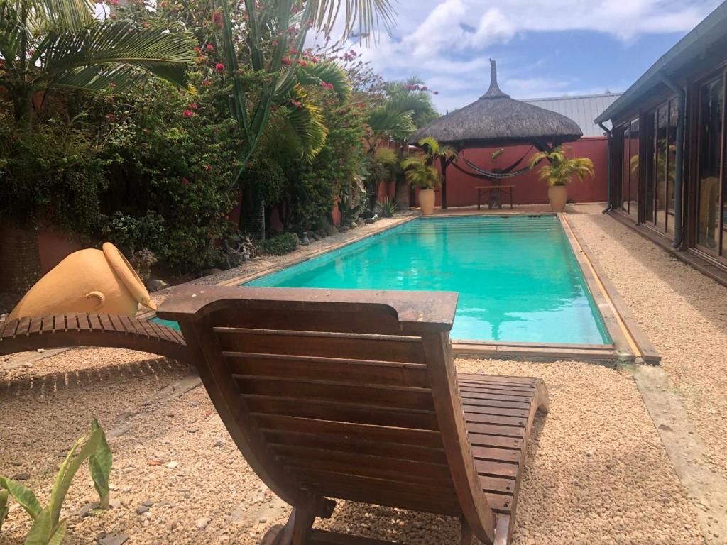 a swimming pool with a chair next to a house at Super villa familiale in Pointe aux Piments