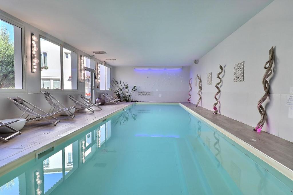 una gran piscina con sillas en un edificio en Grand Hôtel des Bains SPA, en Fouras