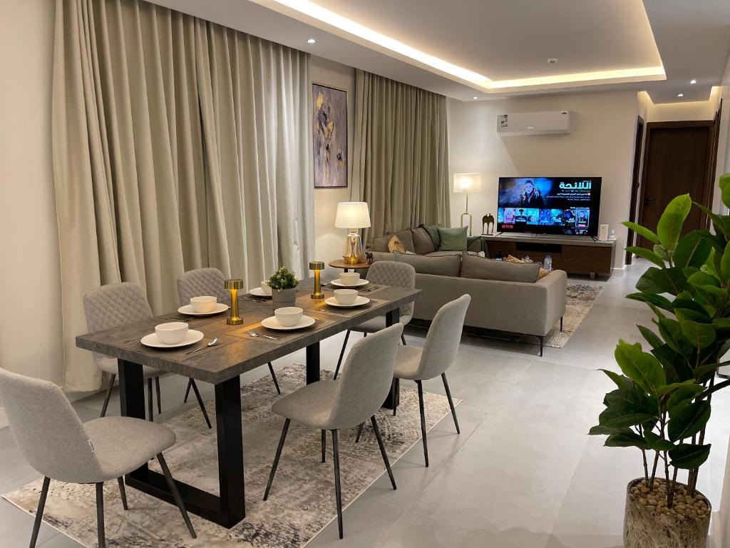 sala de estar con mesa, sillas y sofá en روز رزيدنس, en Riad