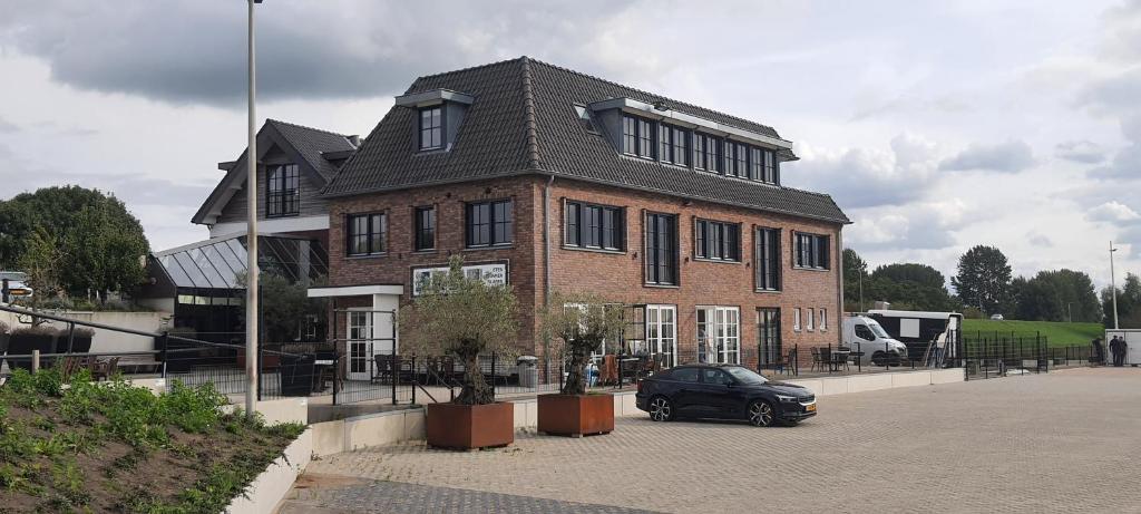 une voiture noire garée devant un bâtiment en briques dans l'établissement Sientjes Boetiekhotel, à Kerkdriel