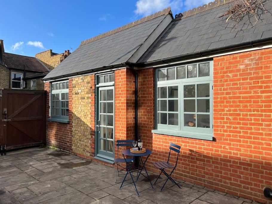 Cette maison en briques dispose d'une terrasse avec une table et des chaises. dans l'établissement Forge Cottage - Pretty 1 Bedroom Cottage with Free Off Street Parking, à Londres