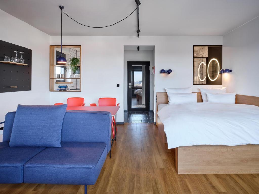 ein Wohnzimmer mit einem blauen Sofa und einem Bett in der Unterkunft STAYERY Wolfsburg City in Wolfsburg