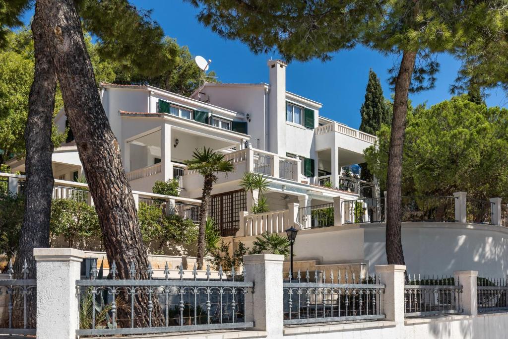 una casa blanca con árboles delante de ella en Apartments Croatia, en Trogir