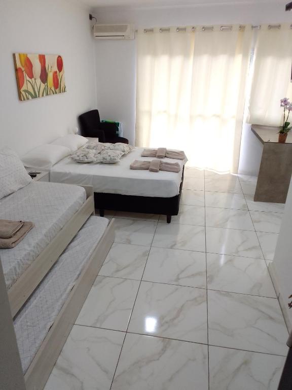 two beds in a room with white tile floors at Tres Fronteras Apart 1 in Puerto Iguazú