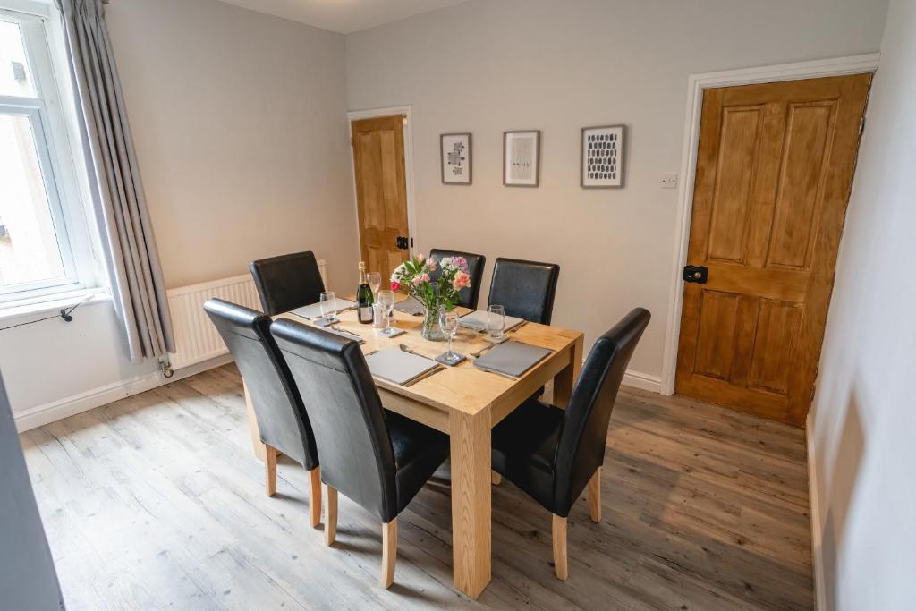 a dining room with a wooden table and black chairs at Seascape Cottage in Haverigg