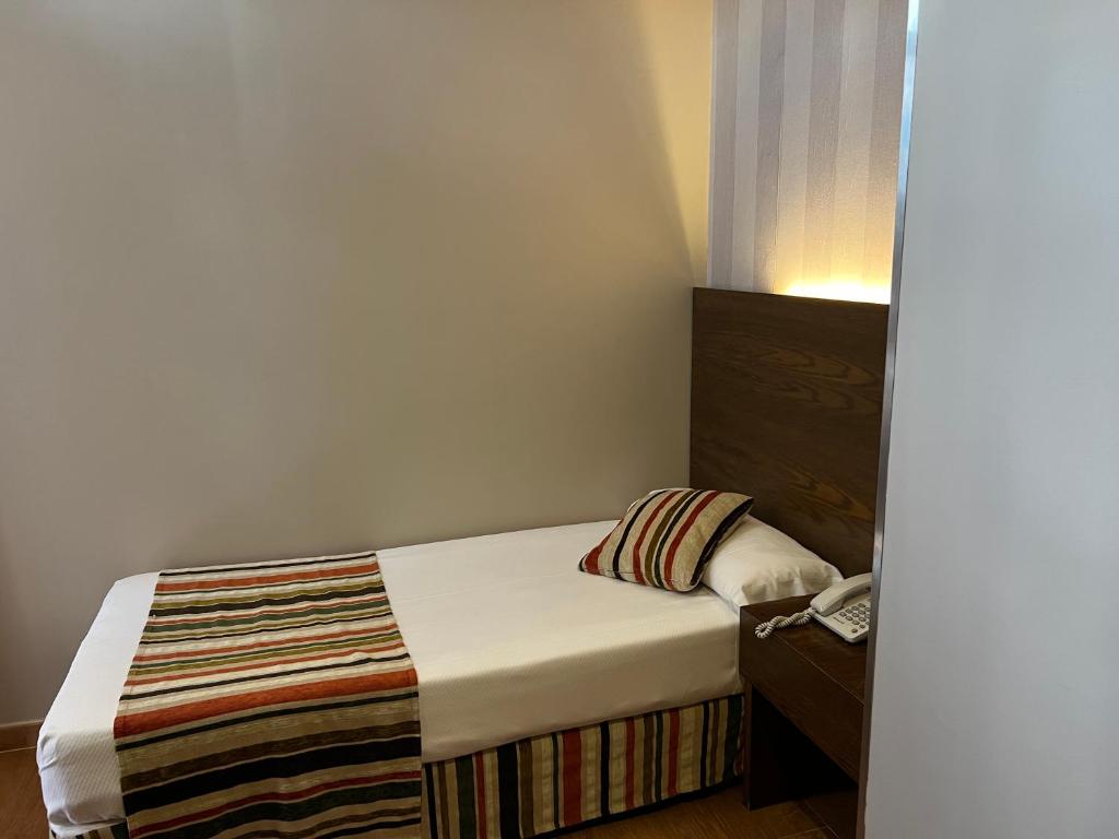 Dormitorio pequeño con cama y teléfono en Hostal Los Coronales, en Madrid