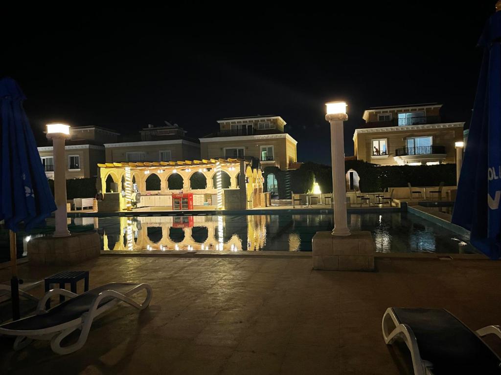 um edifício com piscina à noite com luzes em Beautiful 1-Bed Apartment em Hurghada