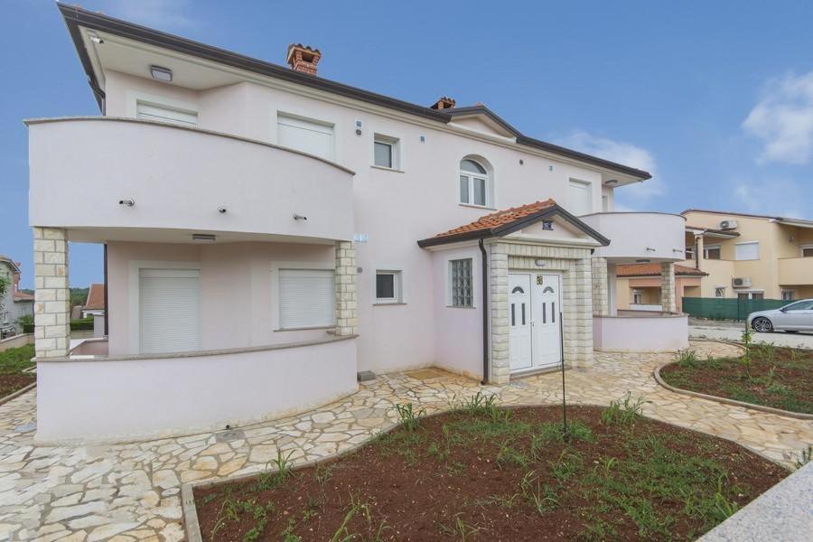 a white house with a garage in a driveway at Villa Filo Apartments in Umag