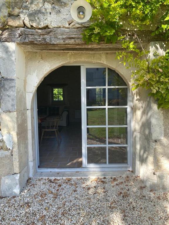a door to a patio in a stone building at Beautiful riverside boathouse in Bourg-Charente