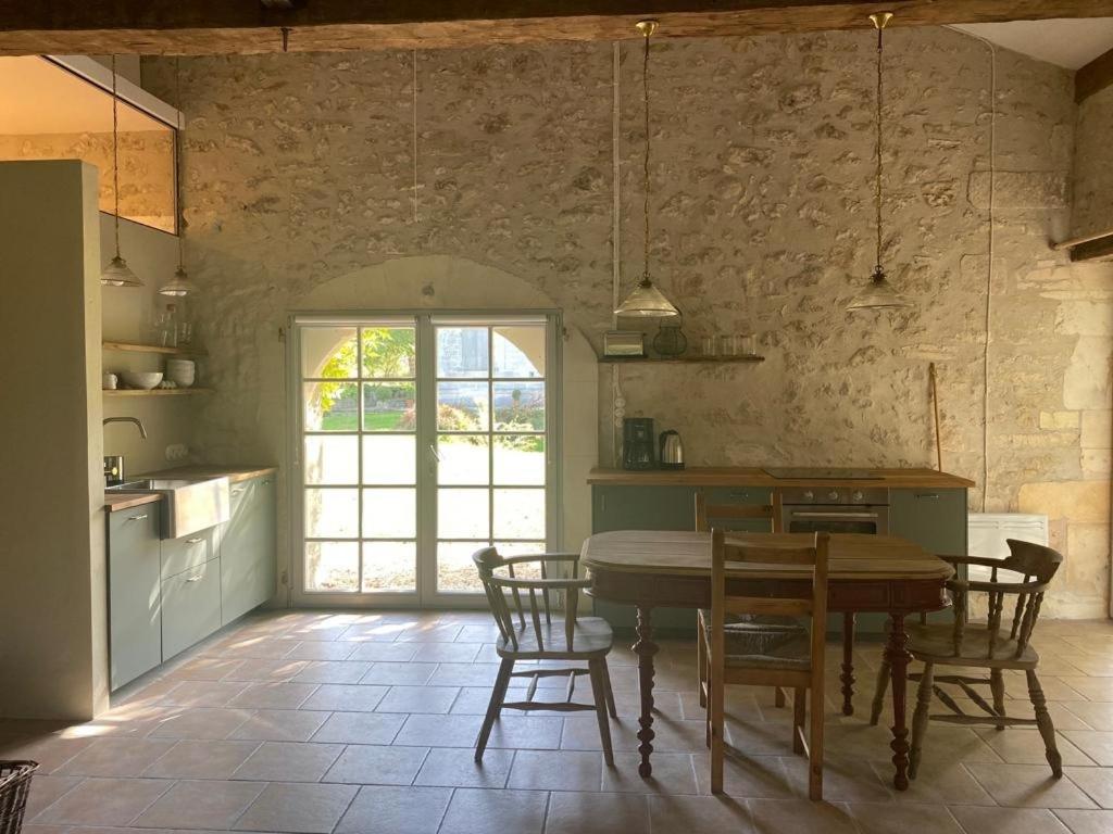 a kitchen with a table and chairs in a room at Beautiful riverside boathouse in Bourg-Charente