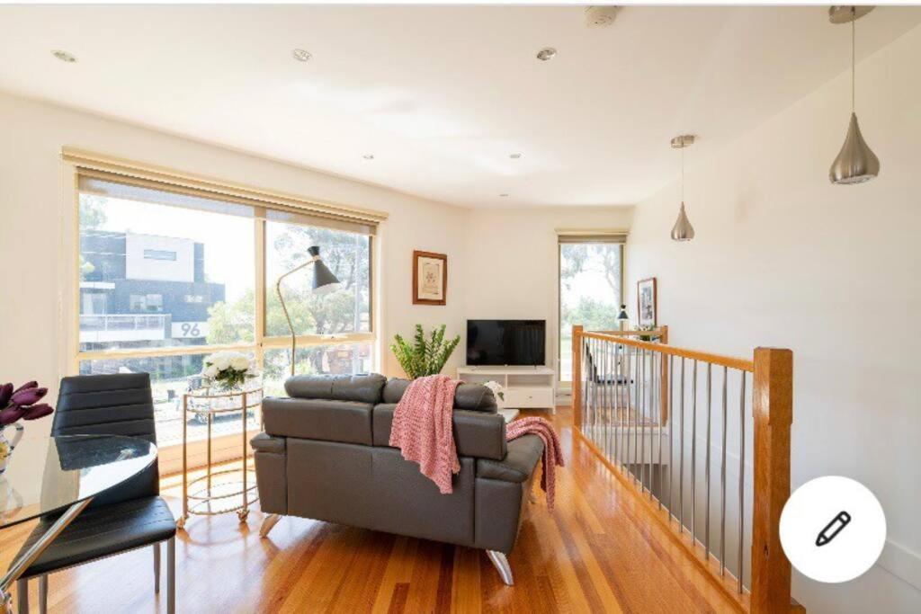 uma sala de estar com um sofá e uma televisão em Design/bright/cosy townhouse between airport &city em Melbourne