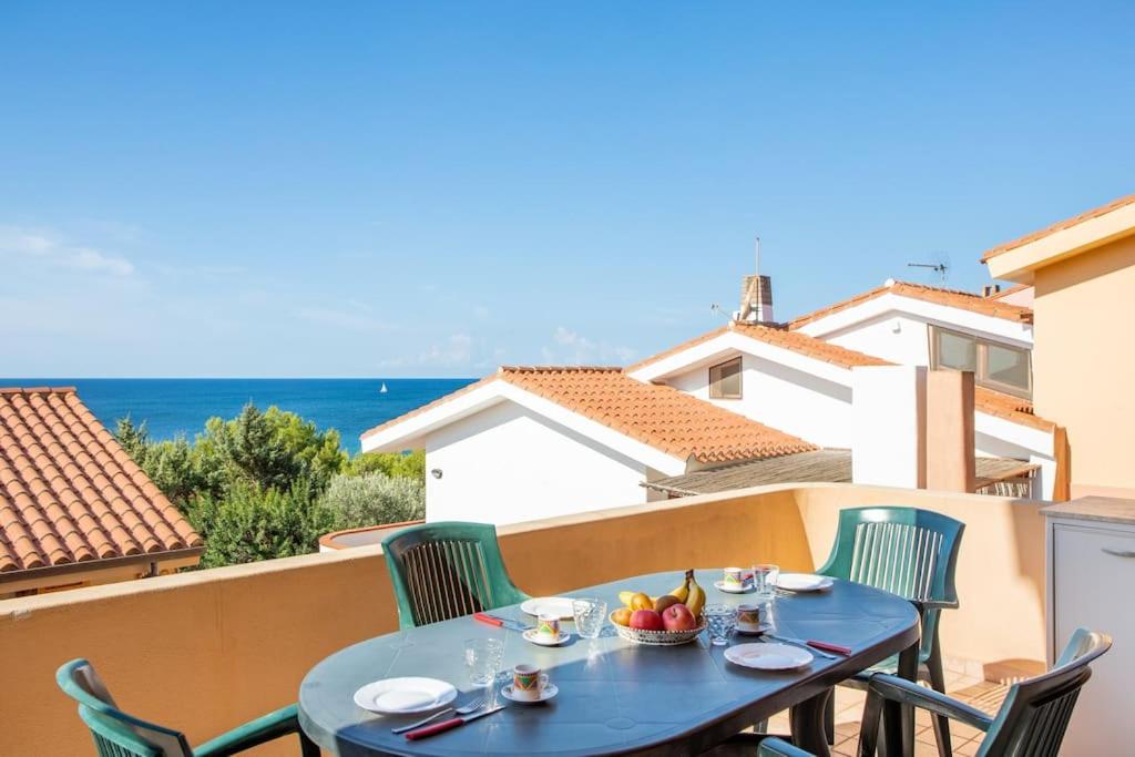 un tavolo blu e sedie su un balcone con vista sull'oceano di Rifugio Marino il tuo angolo di paradiso a Funtana Meiga