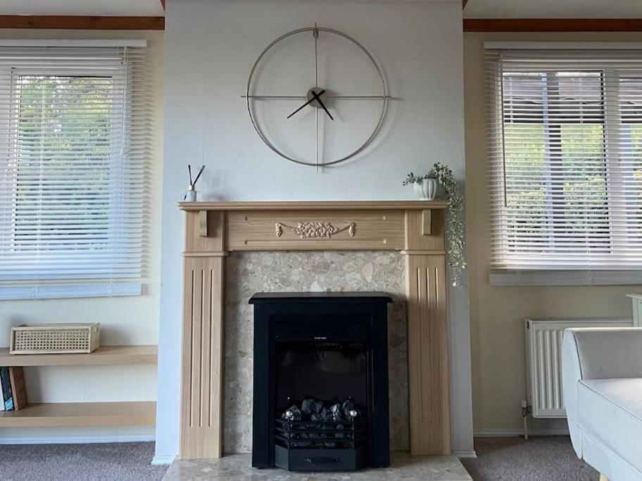a living room with a fireplace with a clock on the wall at Valley View Lodge in Welshpool