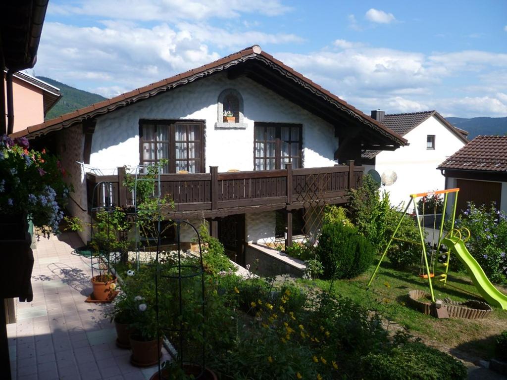 ein weißes Haus mit einer Holzterrasse im Hof in der Unterkunft Ferienwohnung Anita Bernhardt in Rimbach