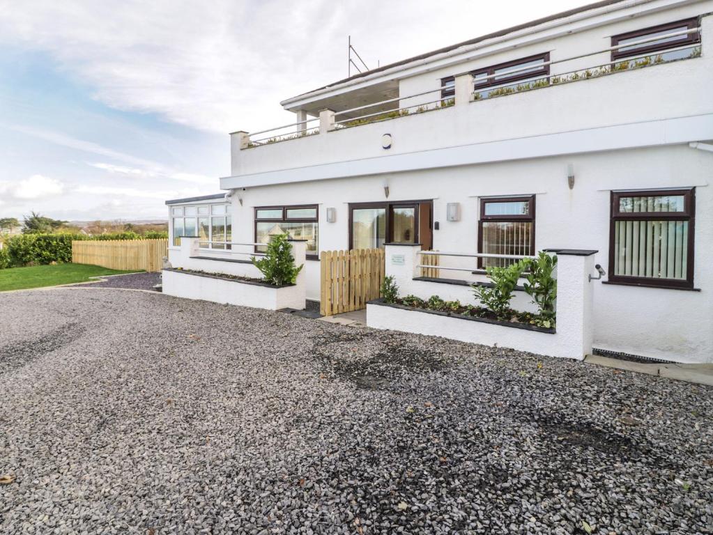 a white house with a gravel driveway at Top Of The Lane Luxury Holiday Apartment in Benllech