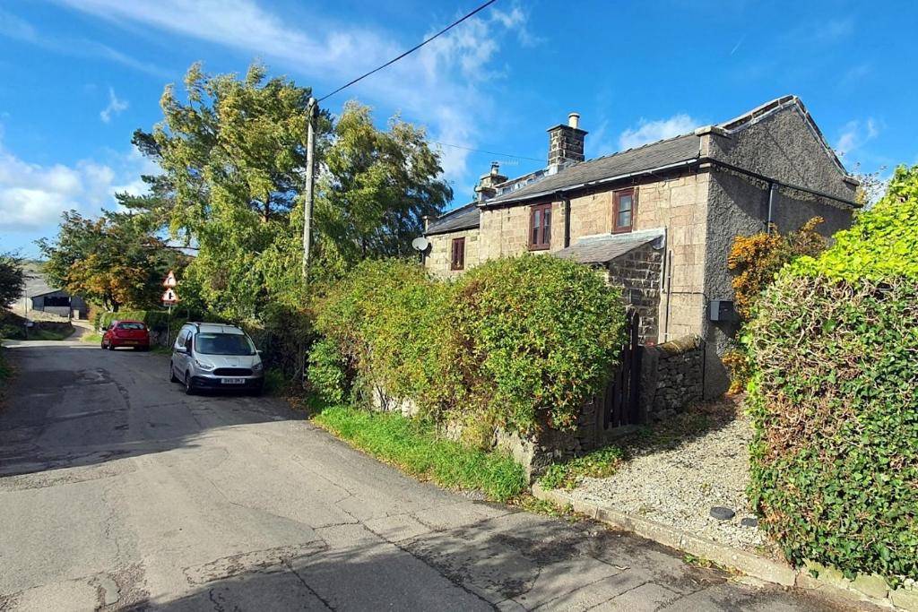 Elton的住宿－Westdale Cottage, Elton in the Peak District，街道边有停车位的房子