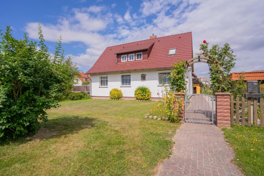 een wit huis met een rood dak en een tuin bij Ferienhaus "Seeadler" in Rankwitz am Peenestrom in Rankwitz