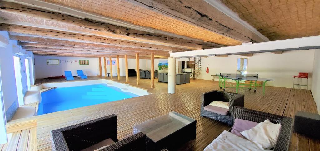 duży basen w pokoju z krzesłami i stołem w obiekcie Grande maison familiale avec piscine couverte w mieście Lespignan