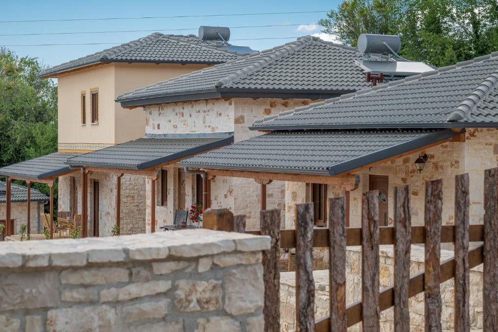 una fila de casas con techos negros y una valla en okakosolykos en Kostitsi