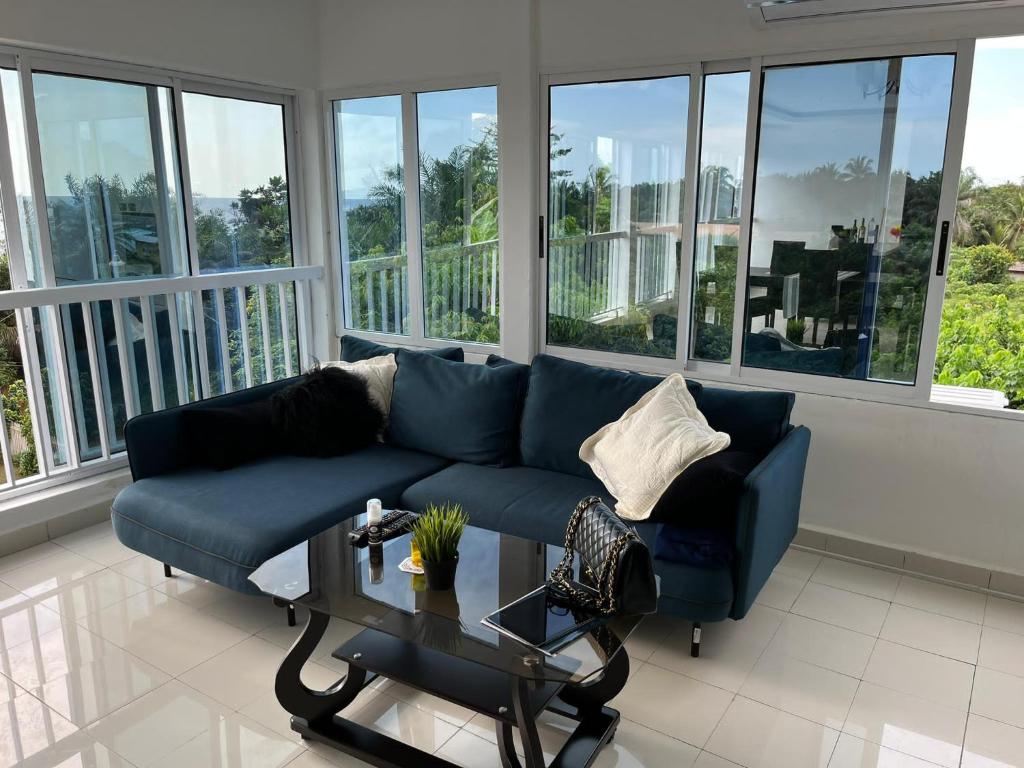 a blue couch in a living room with windows at Swiss Cottage in Kribi