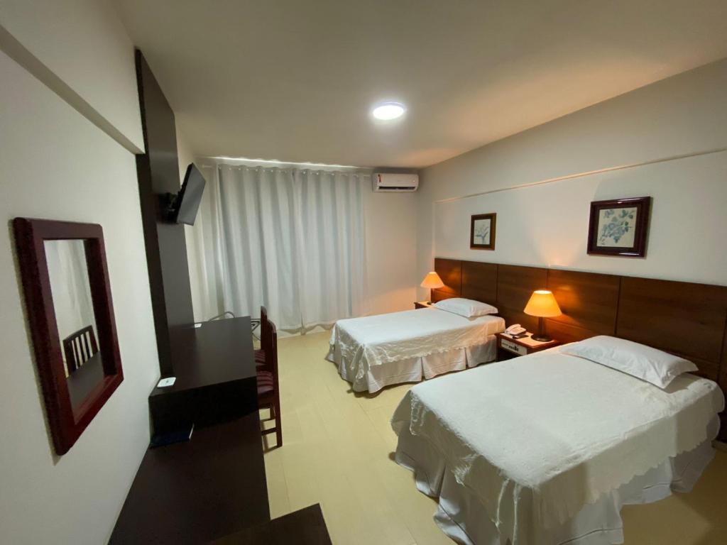 ポルト・ヴェーリョにあるAQUARIUS HOTELのベッド2台と鏡が備わるホテルルームです。