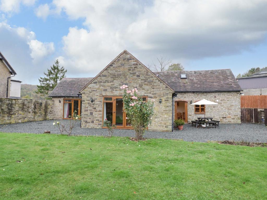 a stone house with a patio and a yard at The Stable in Craven Arms