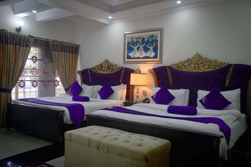 a bedroom with two beds with purple pillows and a couch at Premier Inn Grand Gulberg Lahore in Lahore