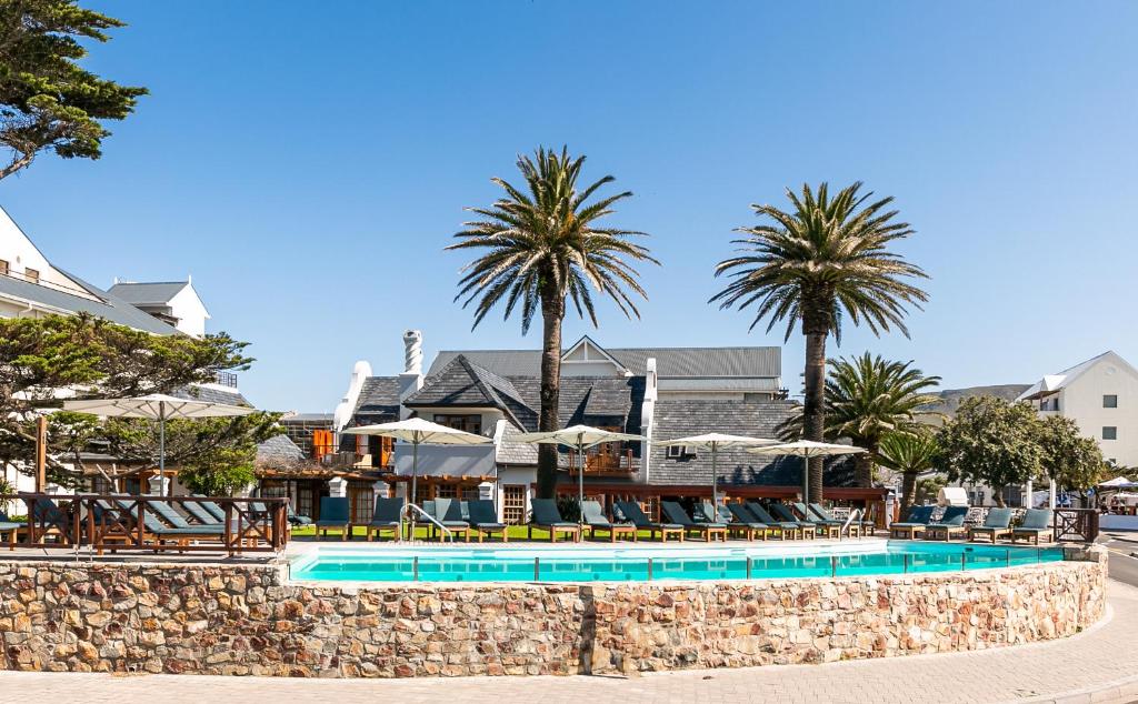 un complejo con piscina y palmeras en Harbour House Hotel - Manor House en Hermanus