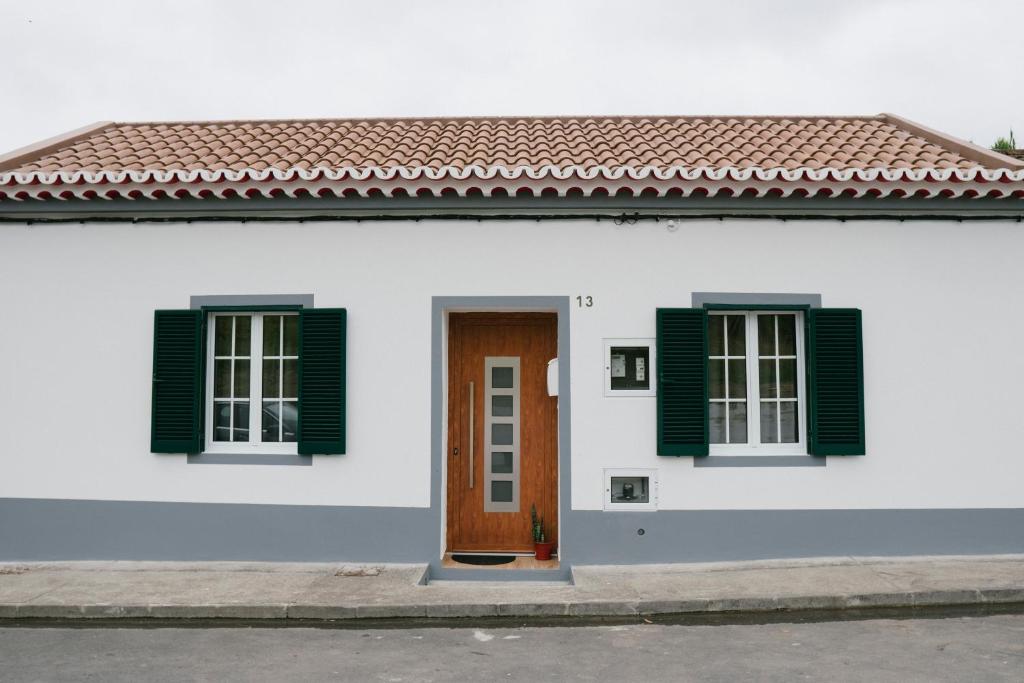 a white house with green shutters and a door at Village House in Ribeira Grande