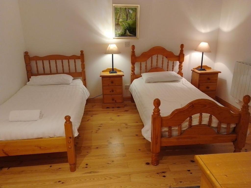 a bedroom with two beds and two lamps on tables at Kearneys Cottage, Dugort, Achill Island, County Mayo - 3 Bedroom Sleeps 6 in Bellanasally