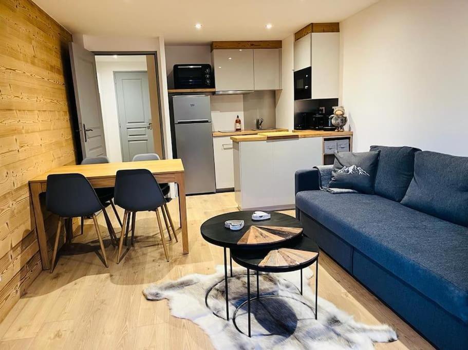 a living room with a blue couch and a kitchen at Appart au centre de la station, entièrement rénové, , parking privé et wifi gratuit in Les Deux Alpes