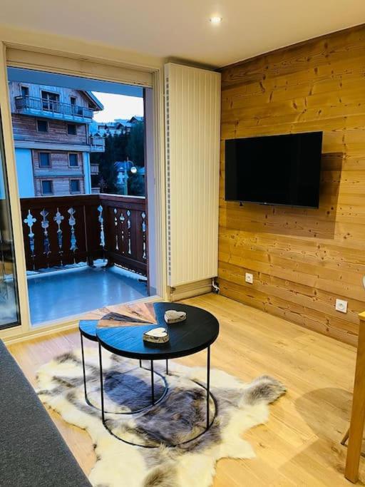 a living room with a table and a flat screen tv at Appart au centre de la station, entièrement rénové, , parking privé et wifi gratuit in Les Deux Alpes