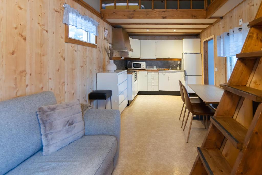 a living room and kitchen with a couch and a table at Aurora River Camp Glass igloos & cabins in Kiruna
