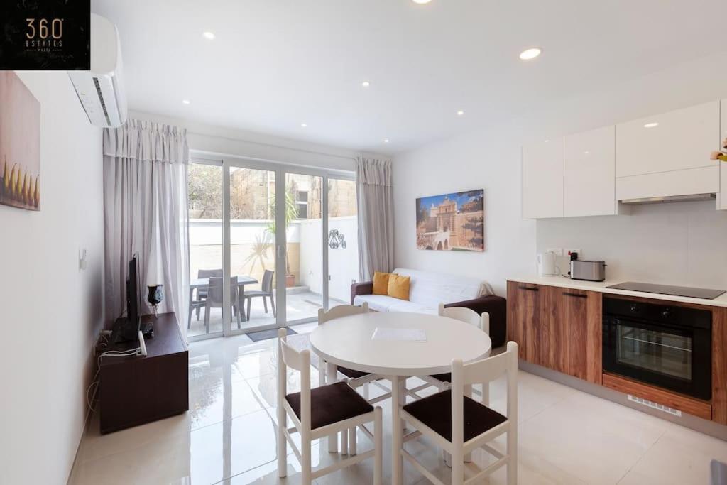 cocina y sala de estar con mesa y sillas en Comfy APT with Terrace, 5 mins to Sliema Ferries by 360 Estates, en Il-Gżira