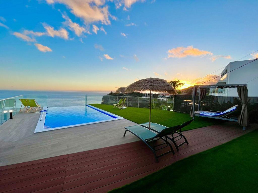 a house with a deck with a view of the ocean at Madeira Sea Sunshine with heated pool in Ribeira Brava