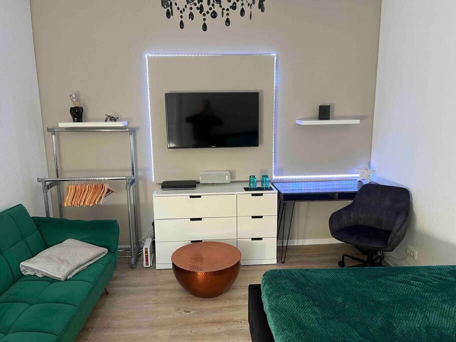 uma sala de estar com um sofá verde e uma televisão em Stadtmitte im Zentrum von Itzehoe aber ruhig em Itzehoe