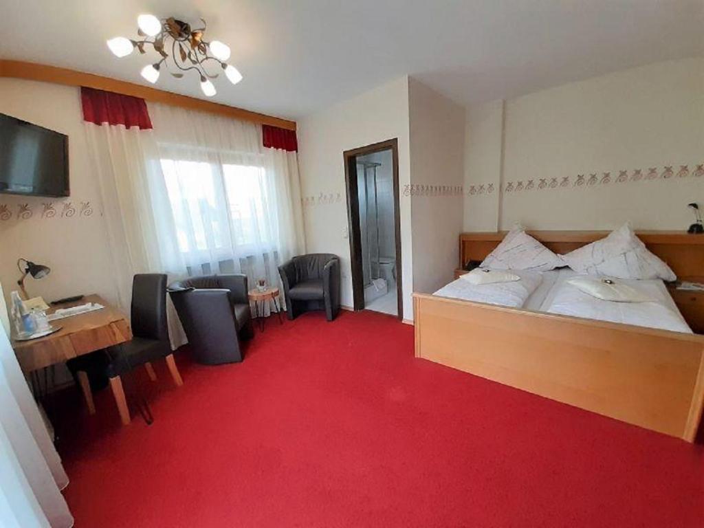 um quarto de hotel com uma cama, uma secretária e cadeiras em Landhotel Neuhof em Zenting