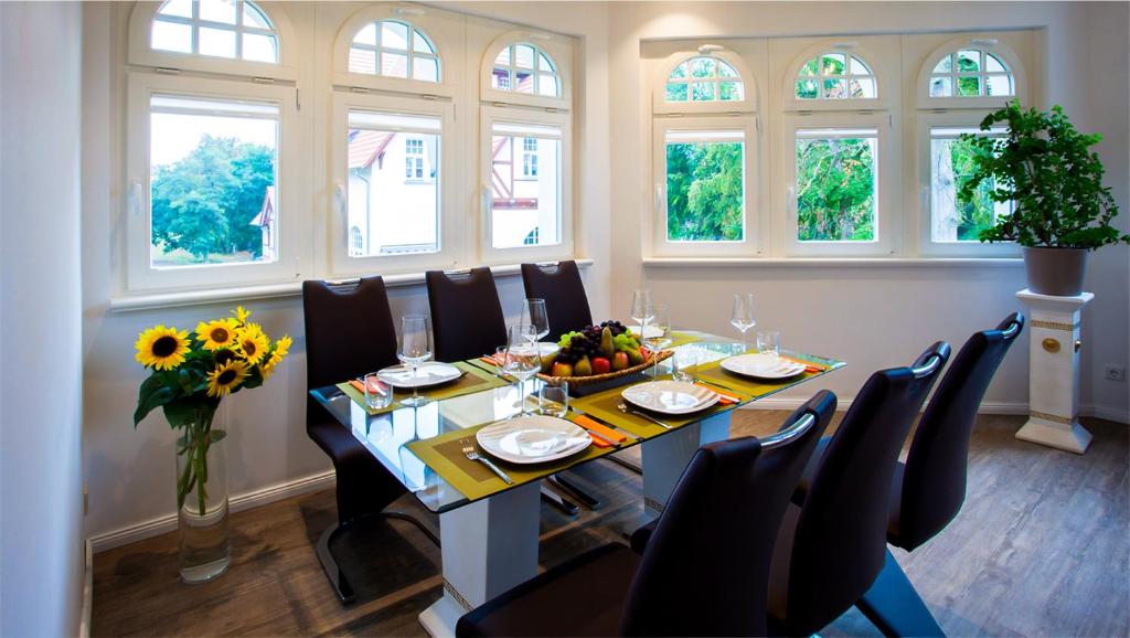 a dining room with a table and chairs and windows at Parkresidenz Lychen, Ferienwohnung 8 in Lychen