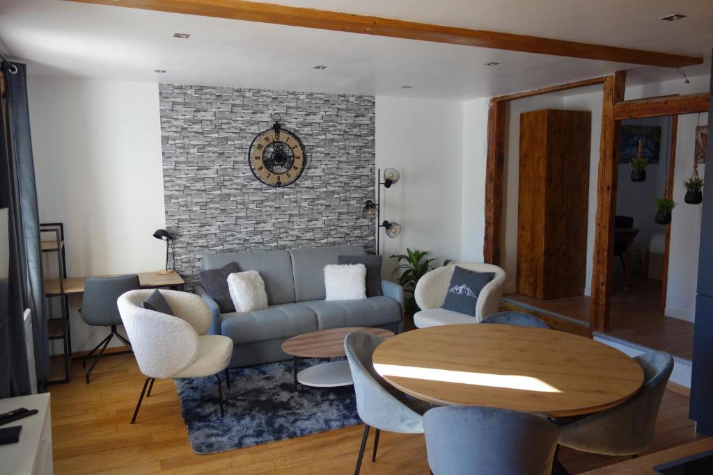 uma sala de estar com um sofá, uma mesa e cadeiras em Chez petit Louis- Appart centre ville jusqu'à 6 personnes em Briançon